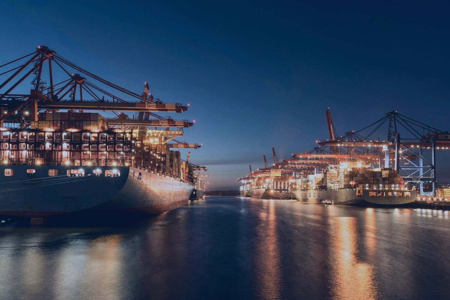Container ships at a lit terminal at dusk
